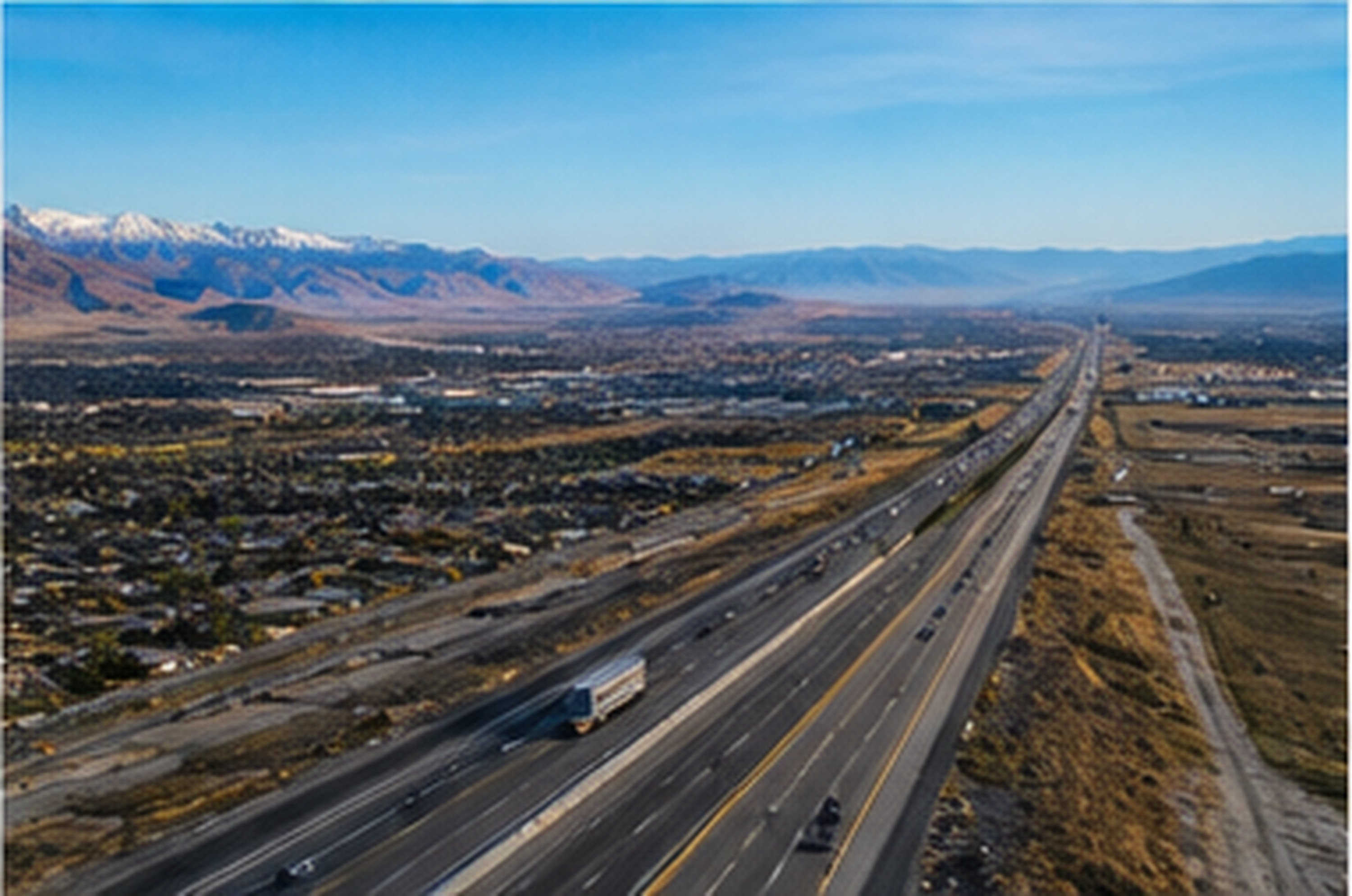 Aerial view of a divided interstate highway running the length of a high-desert valley toward distant mountains